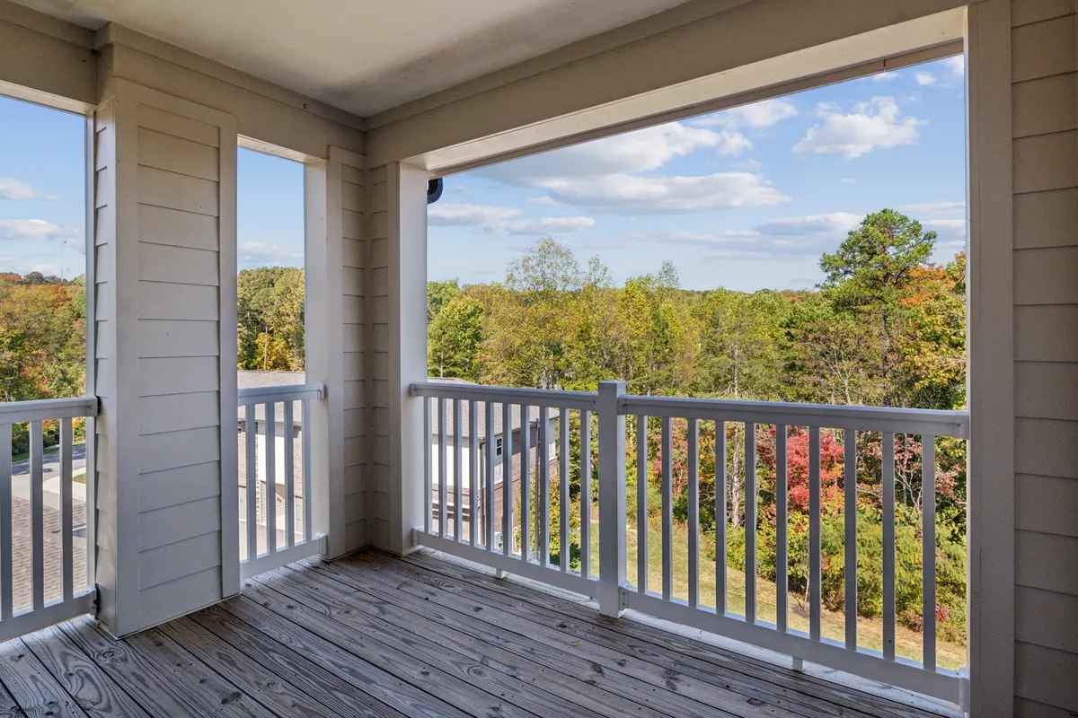 A wooden deck with white railing overlooks a scenic view of trees, suggesting a peaceful spot for enjoying morning coffee, reading, or simply taking in nature. The space feels private yet open to the natural beauty of Farragut's surroundings.