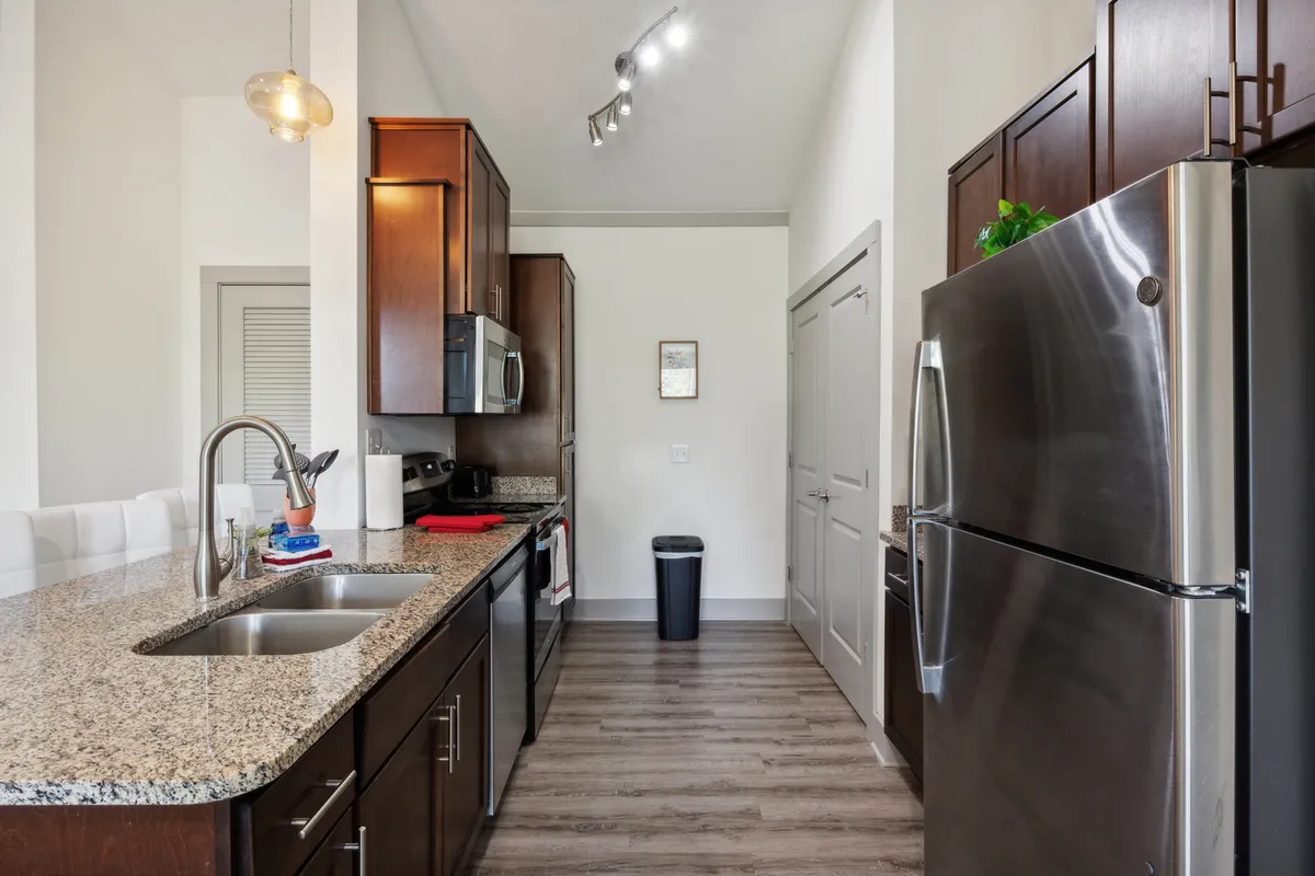 A welcoming kitchen environment with expansive granite countertops, shimmering stainless steel appliances, and contemporary lighting. The space exudes warmth, making it ideal for family gatherings and shared meals, while the well-organized setting displays a sense of readiness for both casual and special occasions.
