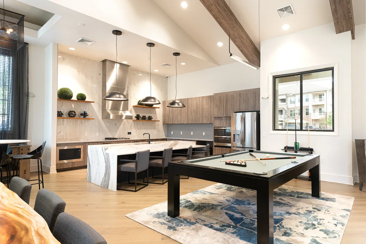 A versatile open-plan interior that includes a kitchen island, a nearby dining area, and a pool table. The layout encourages not only shared meals but also relaxed social gatherings, with the dining space seamlessly integrated with areas for fun and conversation.